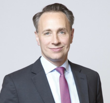 Portrait of Thomas Buberl, Chief Executive Officer and Director of AXA, standing confidently in a professional setting, symbolizing leadership and innovation in the insurance industry.