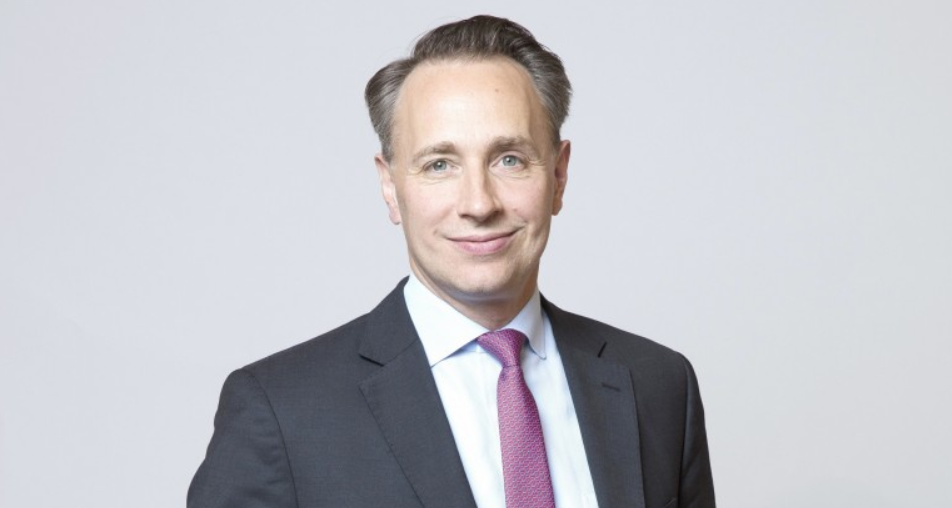 Portrait of Thomas Buberl, Chief Executive Officer and Director of AXA, standing confidently in a professional setting, symbolizing leadership and innovation in the insurance industry.