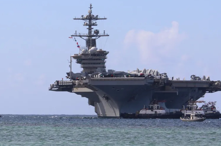 Harbour tugboats escort the Nimitz-class aircraft carrier USS Abraham Lincoln as it arrives at the US Naval Base in Guam for a scheduled port visit.